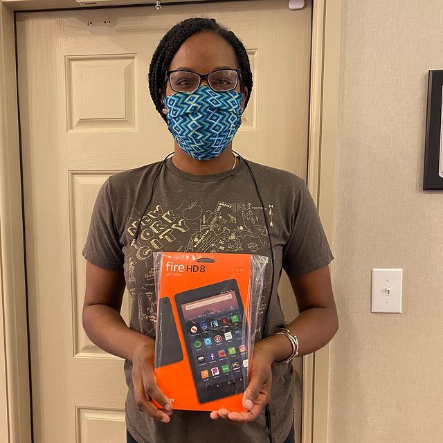 African-American girl with a mask on her face holding a box with a tablet